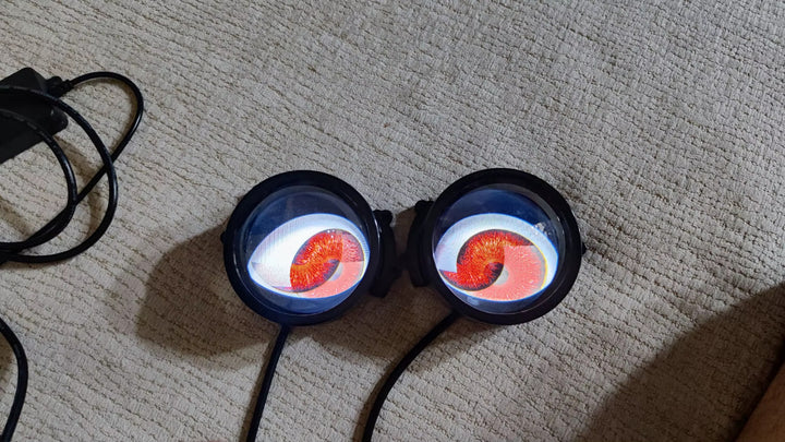 A pair of devil eye lenses lit red on the floor, wired to a battery for a first test - customer photo